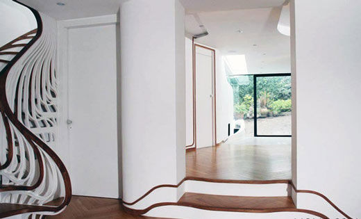 这个独特的楼梯在住宅空间中扭动，并将自己流动的形态与地脚线图案有机的融为一体。为了与已有的空间布置相协调，设计师希望在视觉上将这个楼梯间和其它生活空间联系起来，楼梯扶手向下延伸到浴室中，并顺着墙面伸展开来，缠绕了周边的家具，将本身的形态完全融入到空间中。