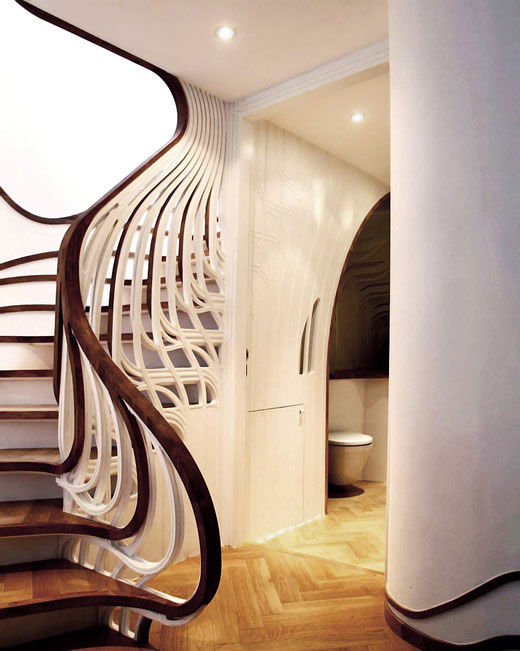 这个独特的楼梯在住宅空间中扭动，并将自己流动的形态与地脚线图案有机的融为一体。为了与已有的空间布置相协调，设计师希望在视觉上将这个楼梯间和其它生活空间联系起来，楼梯扶手向下延伸到浴室中，并顺着墙面伸展开来，缠绕了周边的家具，将本身的形态完全融入到空间中。